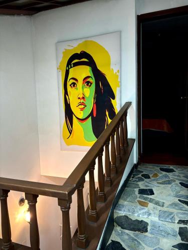 a painting of a woman on a wall next to a staircase at Kuyay Yachi Hostel in Bogotá
