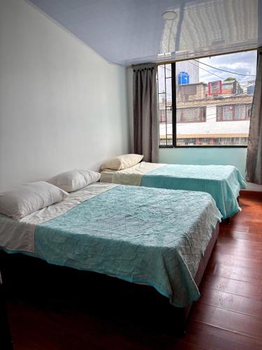 two beds in a room with a window at Kuyay Yachi Hostel in Bogotá