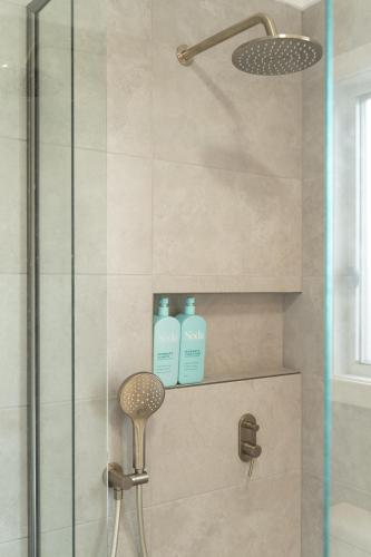 a bathroom with a shower with two bottles of soap at Cute Coastal 2-Bedroom Getaway in Ettalong Beach