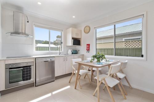 a kitchen with a table and chairs and a window at Cute Coastal 2-Bedroom Getaway in Ettalong Beach