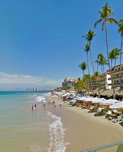 a beach with people and umbrellas and the ocean at Balcony GrandiaHouse in Puerto Vallarta