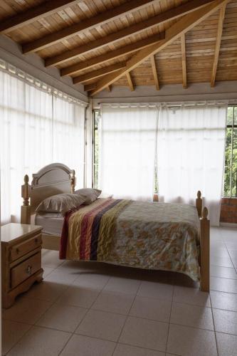 a bedroom with a bed in a room with windows at Finca campestre de 2 pisos en Guarne in Guarne
