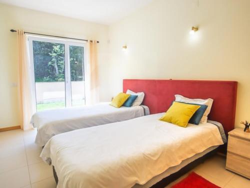 zwei Betten in einem Zimmer mit Fenster in der Unterkunft Casa Aromas do Mar, Burgau in Burgau