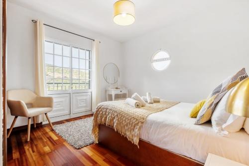 a white bedroom with a bed and a chair at Sea View Villa by Homie in Santa Cruz