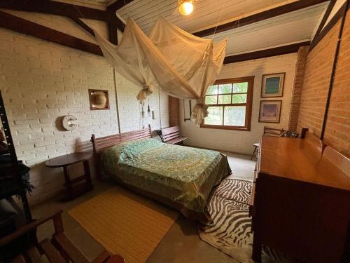 a bedroom with a bed and a table and a window at Casa Charmosa ao lado da Villa Mandacaru in Itu