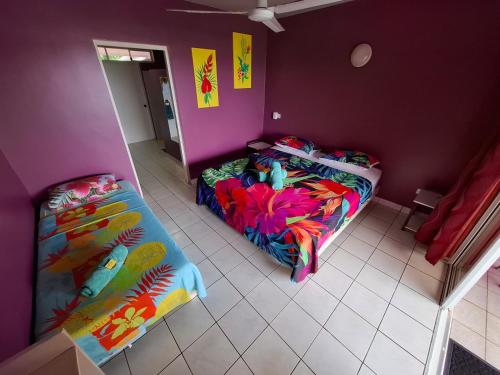 two beds in a room with purple walls at Pension Tautiare Village in Maupiti