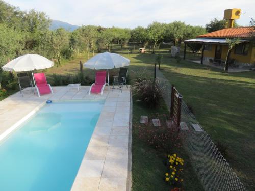 a pool with chairs and umbrellas in a yard at Arawi Cabaña in Merlo