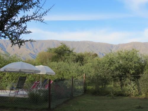 a patio with an umbrella and a view of mountains at Arawi Cabaña in Merlo