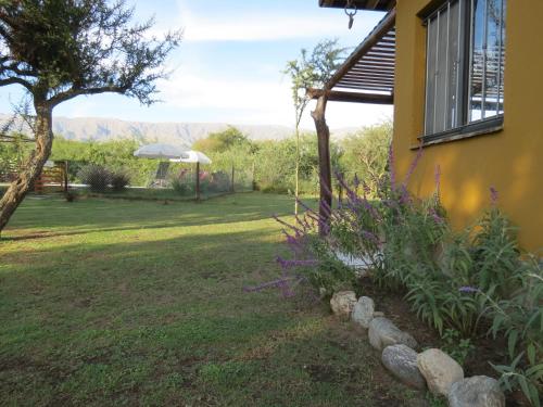 a yard with a yellow house and some flowers at Arawi Cabaña in Merlo