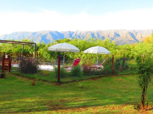 two chairs and umbrellas in a yard with mountains in the background at Arawi Cabaña in Merlo