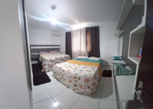 Una pequeña habitación con dos camas y un espejo. en Casa praia, en Barra Velha