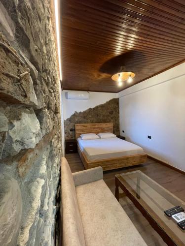 a bedroom with a bed and a stone wall at Villa Çabeli in Gjirokastër