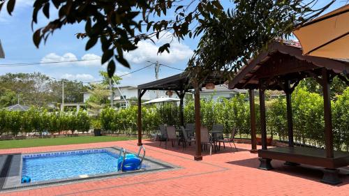 ein Schwimmbad mit Pavillon und Haus in der Unterkunft LAMAN KASEH Homestay Bukit Katil 4bedroom with Swimming Pool in Ayer Keroh