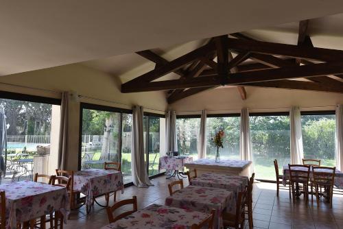 a dining room with tables and chairs and windows at Hôtel PRATO PLAGE in Pernes-les-Fontaines
