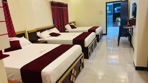 a group of four beds in a room at Hotel SONIA MAHI INN KANYAKUMARI in Kanyakumari