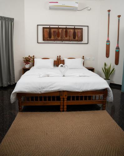 a bedroom with a large bed with white sheets at Paddle Cult Surf & Yoga in Varkala