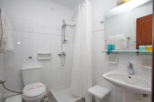 a white bathroom with a toilet and a sink at Hotel Anelli in Skopelos Town