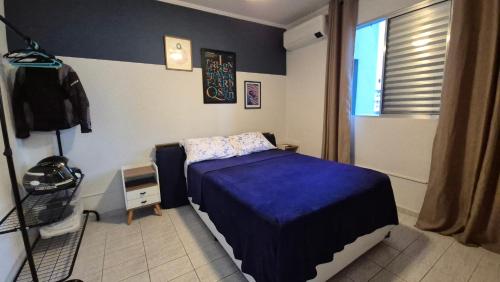 a bedroom with a blue bed and a window at Apto a 5min da praia da Pompeia in Santos