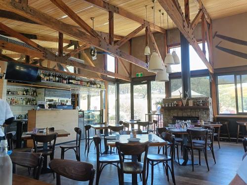 a restaurant with tables and chairs in a room with windows at Monument Chalet in Crakenback Resort in Crackenback