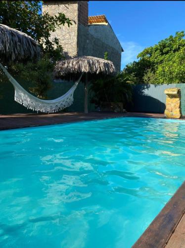 a swimming pool with a hammock and a house at Chalés da Cris in Fortim