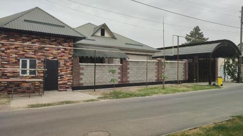 a brick building with a gate next to a street at "Aiko" Қонақ Отбасы 2 in Shymkent