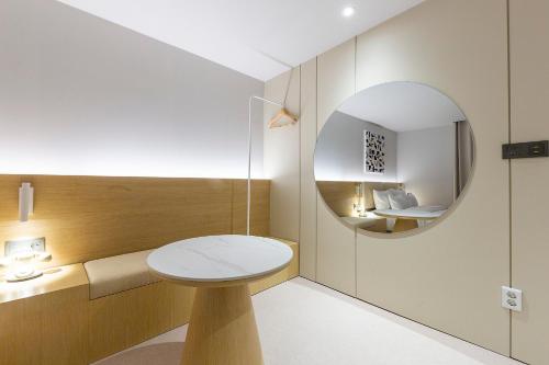 a bathroom with a round mirror and a white sink at Browndot Cheonan Terminal in Cheonan