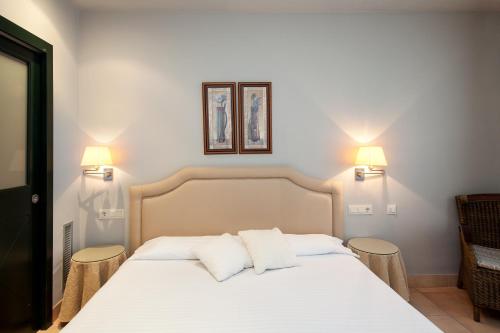1 dormitorio con 1 cama blanca y 2 almohadas en Apartahotel Suites Vila Birdie, en Navata