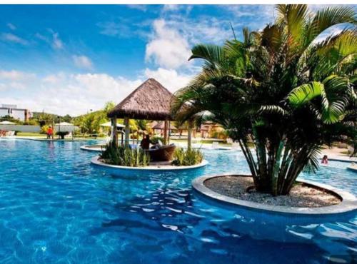 a resort pool with a palm tree and a gazebo at Iloa Flat Resort Apt 207 bloco H in Barra de São Miguel