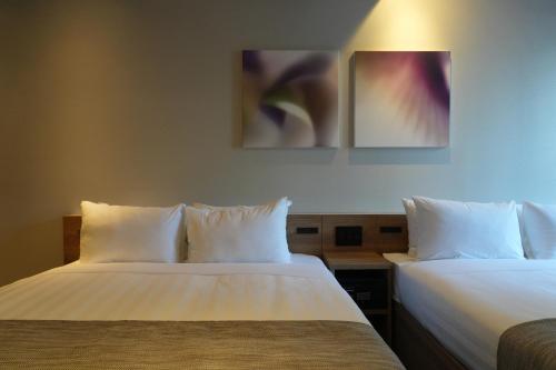 two beds sitting next to each other in a room at Premium Apart MONday GINZA EAST in Tokyo