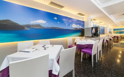 a restaurant with white tables and purple chairs and a mural at Globales Palmanova in Palmanova