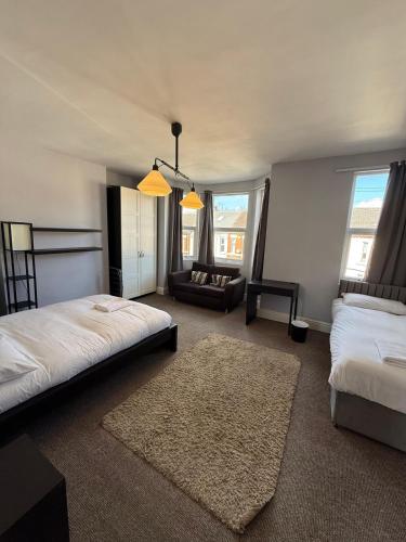 a bedroom with two beds and a couch and windows at 5BR, Spacious with Free Parking in Coventry