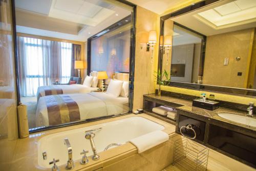 a bathroom with a tub and a bed and a mirror at Wanda Vista Quanzhou in Quanzhou