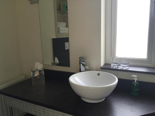 a white bowl on a black counter in a bathroom at Quinlan & Cooke Boutique Townhouse and QCs Seafood Restaurant in Cahersiveen