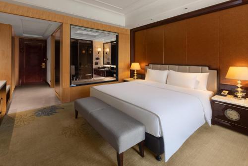 a bedroom with a large white bed and a bathroom at Wanda Vista Quanzhou in Quanzhou