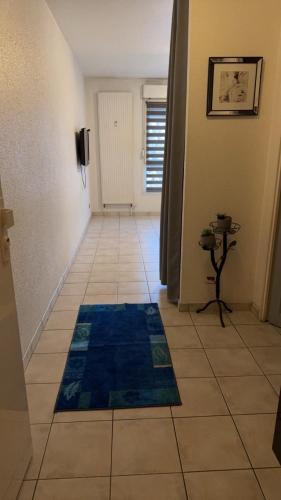 un couloir avec un tapis bleu sur un sol carrelé dans l'établissement Studio meublé, à Mulhouse