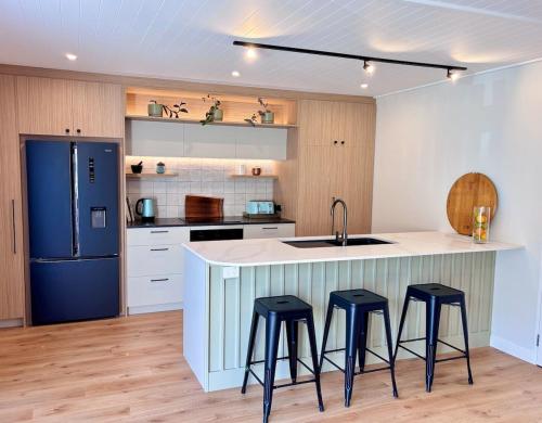 a kitchen with three bar stools and a blue refrigerator at Central City Queenstown Retreat - 3 Bedroom Apartment in Queenstown