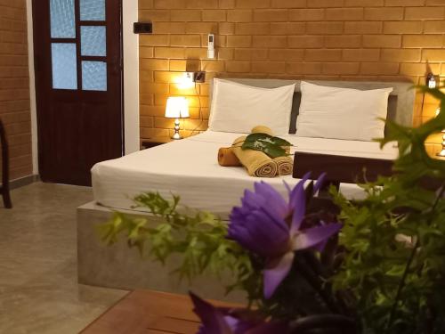 a bedroom with a bed with white sheets and purple flowers at Villa Sol in Kamburugamuwa