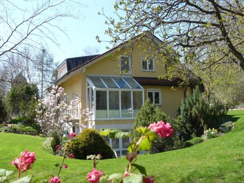 een geel huis met bloemen in de tuin bij Haus Ahorn in Bad Dürrheim