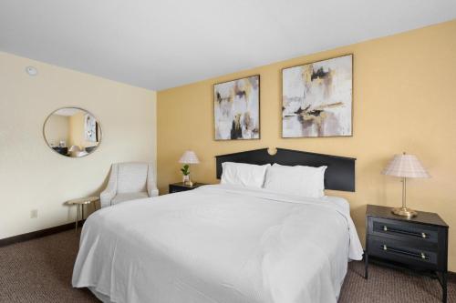a bedroom with a large white bed and a chair at StayInn Grand Forks in Grand Forks