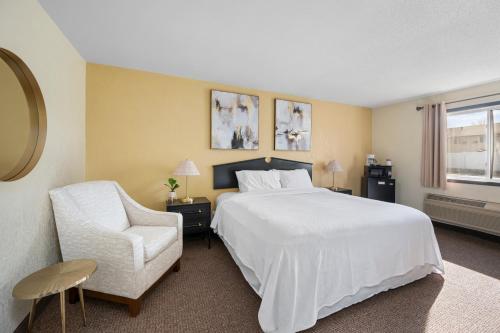 a bedroom with a large white bed and a chair at StayInn Grand Forks in Grand Forks