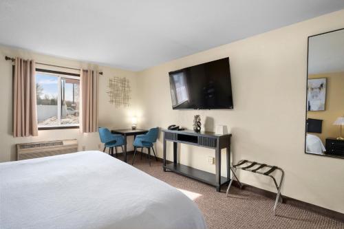 a hotel room with a bed and a desk and a television at StayInn Grand Forks in Grand Forks