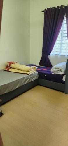 two twin beds in a room with a window at Homestay Ummi Baling in Baling