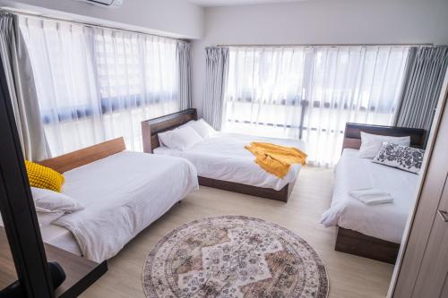 a small bedroom with two beds and a window at ORI Nipponbashi in Osaka