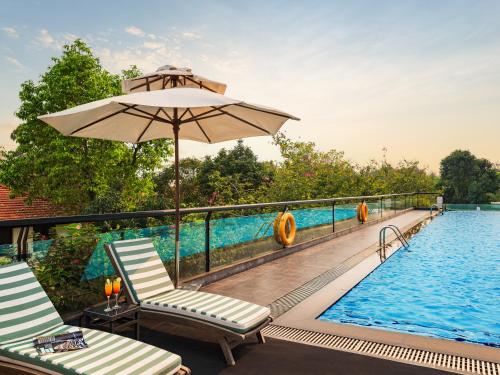 a swimming pool with two chairs and an umbrella at Elegant Suites Westlake in Hanoi