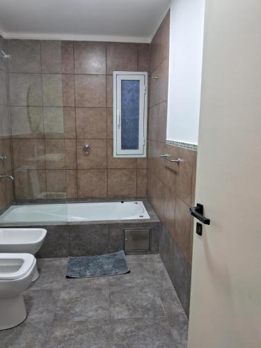 a bathroom with a tub and a toilet and a window at Casa en Venado Tuerto in Venado Tuerto
