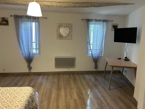 une chambre avec des rideaux bleus, un bureau et une télévision dans l'établissement Maison de ville 3 chambres, à Carpentras