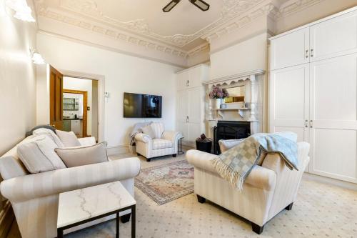 a living room with white furniture and a fireplace at Washington Cottage in Angaston