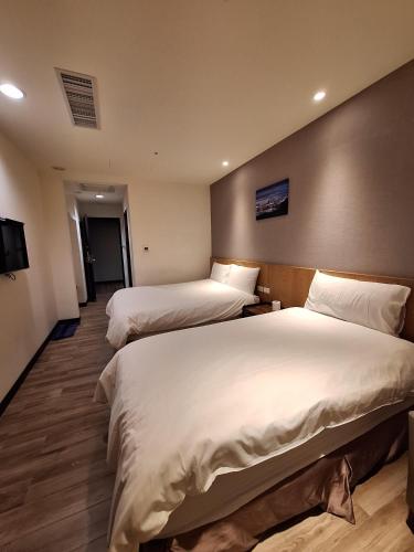 a hotel room with two beds and a television at Honest & Warm Hotel in Taoyuan