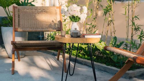 a chair and a side table with a vase of flowers at House of Pi Pleiku in Pleiku