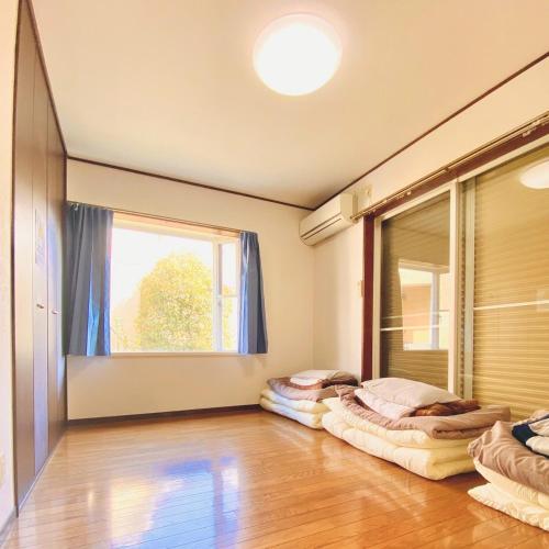 two beds in a room with a window at 木の家ゲストハウス宇都宮2号館 in Utsunomiya